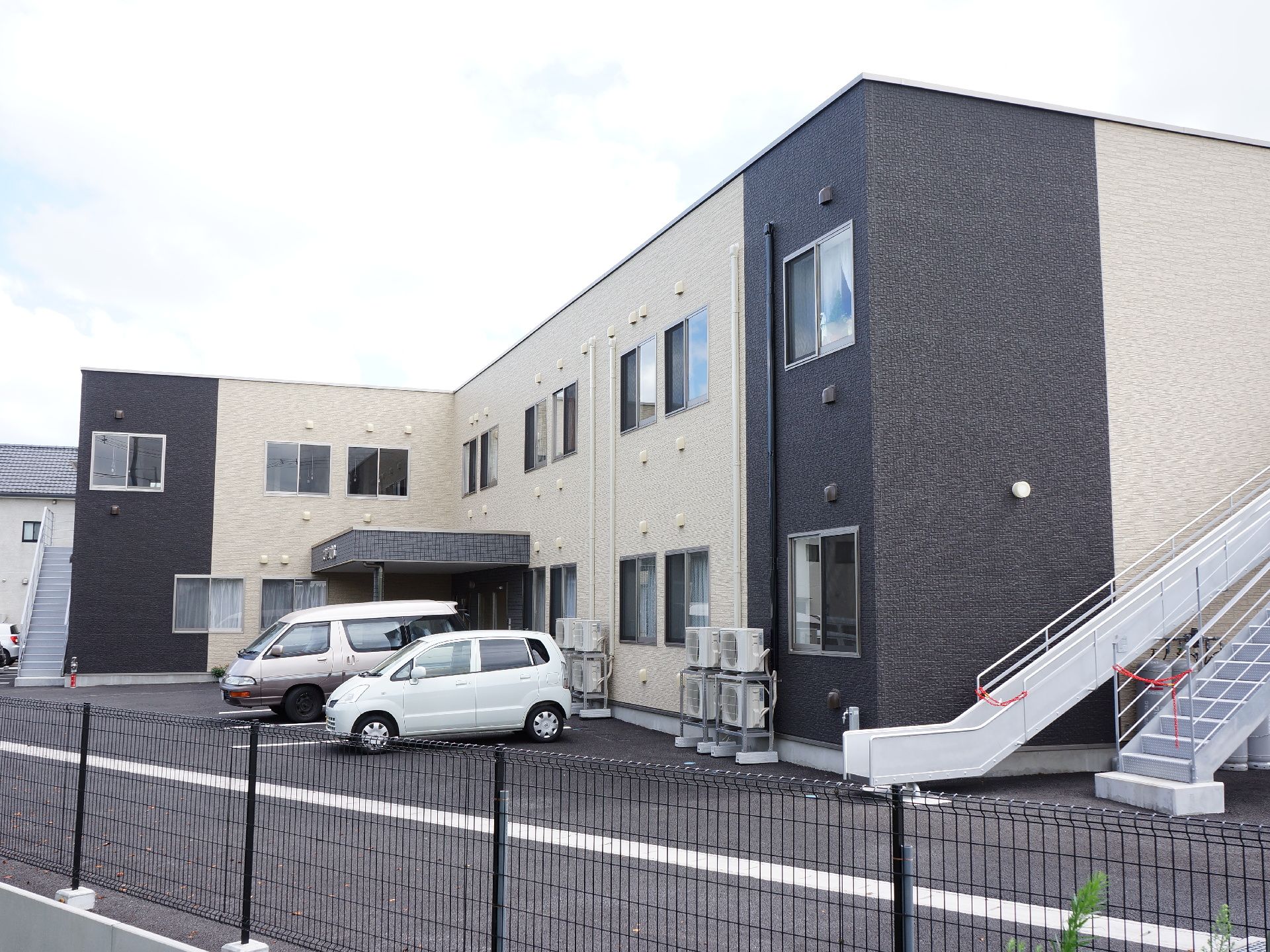紺と白基調の２階建ての施設になっている。窓が多くあり、駐車場もある。非常用の階段と滑り台が設置されている。