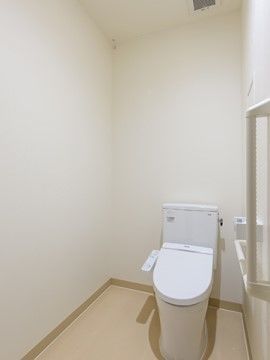 白系で統一された、清潔感のある温水洗浄便座付きのトイレ。壁には立ち座りの時に便利な手すりが設置されている。