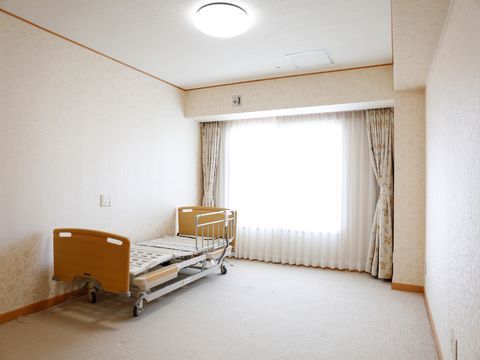 介護用ベッドが設置された室内には、太陽の光が差し込む大きな窓があり、遮光カーテンが備え付けられている。