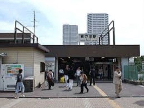 駅前に自動販売機が置かれている。アスファルトで舗装された道には、黄色い点字ブロックが設置されている。