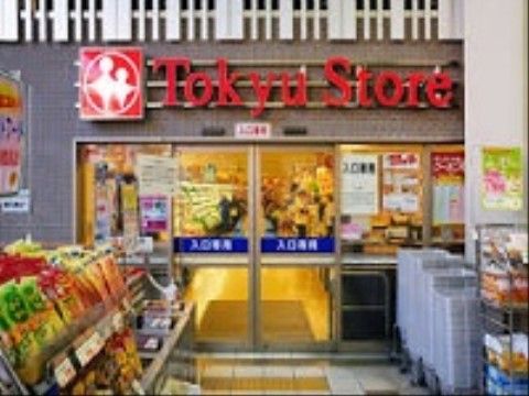 スーパーマーケット入口の写真である。自動ドア前に商品が並べられており、買い物かごも積まれて用意されている。