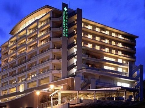 夜に撮影されたグループホームの写真。建物の横には大きな看板が設置されており、施設内から明るい光が漏れている。