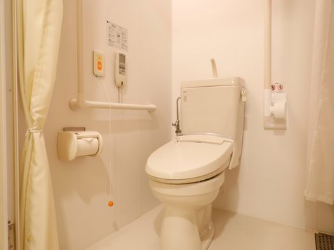 白色で統一されたトイレスペースです。横側の壁にはエル型、後部には縦型に手すりが設置してある。また、カーテンで仕切るようになっている。