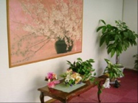 玄関には赤いカーペットが敷かれており、木のローテーブルが置かれている。花瓶の花を描いた大きな絵が壁に飾られている。