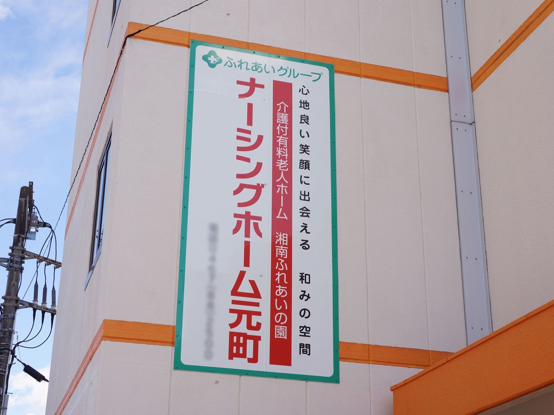 外にある看板の様子。看板は施設外壁に取り付けられている。施設名と施設方針のキャッチコピーが描かれている。
