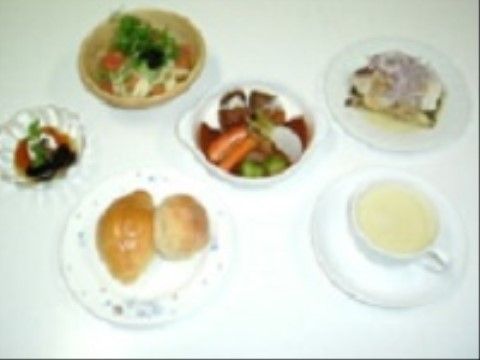 白いテーブルの上に、ロールパンやスープ、ポトフといった洋食メニューの食事が並べられている。彩りや栄養バランスを考えて作られている。