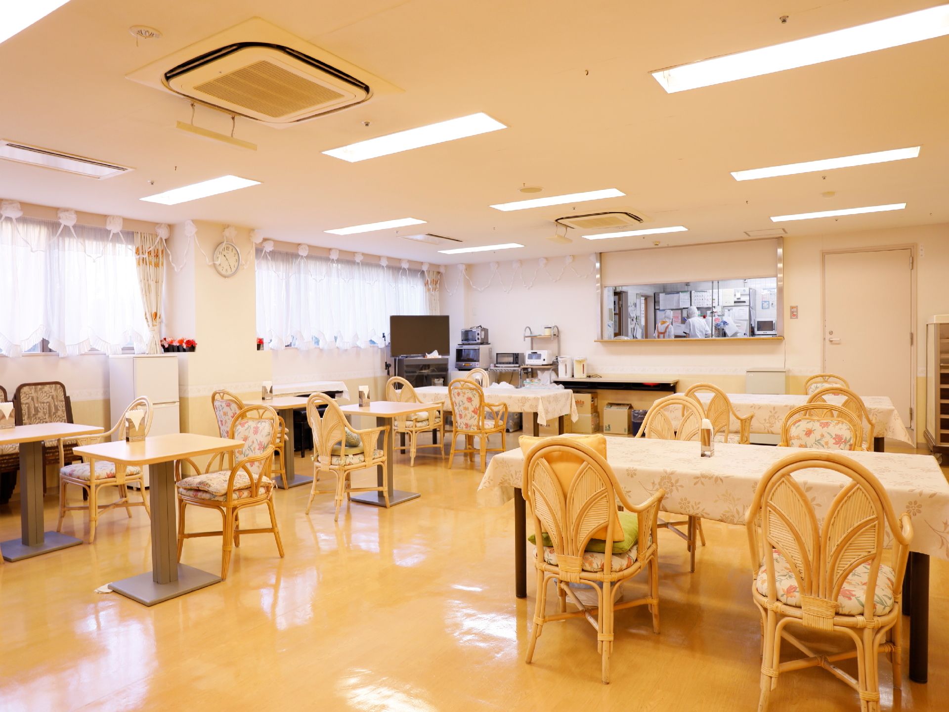 壁一面に窓が設置されている。食堂の奥には調理室があり室内が見える窓がある。テーブルと椅子が幾つも食堂内に置かれている。