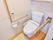 カーテンで仕切られたトイレスペースは、両手に手すりが付いている。緊急用ブザーが付いている。高齢者に優しいウォシュレット。