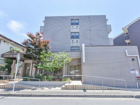 正面玄関、裏玄関にスロープと階段がある。木と花が植えられた花壇がある。4階建て鉄筋コンクリート造り。