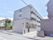 4階建て鉄筋造り。建物前にスロープがある。薄い灰色の外壁である。施設看板が道路から見えるところに配置されている。