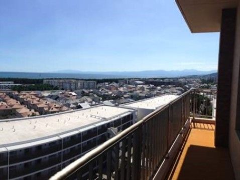 ベランダからは、海や遠くに見える山の連なりが眺められる。階下には緑が広がり、住宅が並んでいるのが見えている。
