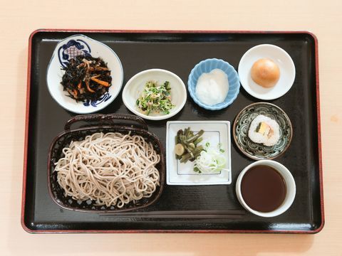 ある日の食事メニュー。メインはそば、とろろ、山菜、ひじきの煮物、和え物、太巻き、おまんじゅうなどのメニューとなっている。
