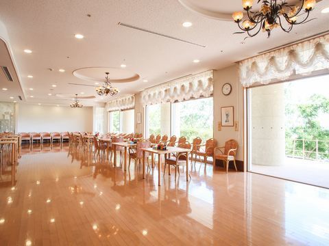 大きな窓がたくさんあり、電灯はシャンデリアを使用している。木目調のテーブルと花柄の椅子がある。床はフローリング。