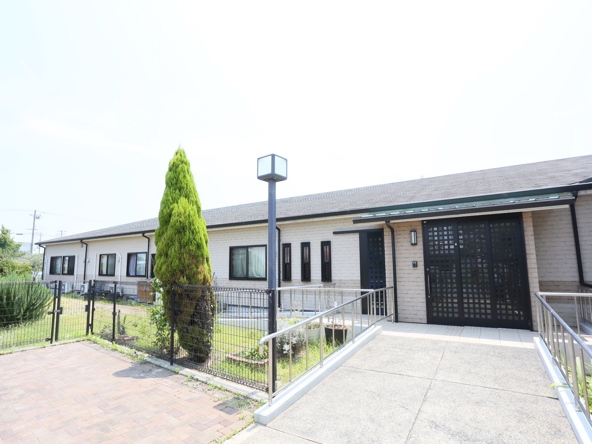 施設は平屋建て。幅広いスロープは傾斜が緩やかで、両端に手すりがある。中庭はフェンスで囲まれている。玄関先に街灯がある。