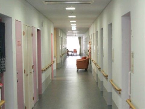 空調と照明を天井に埋め込み型にすることで、すっきりとした印象の通路。白とグレーの壁紙と、ピンクの扉が柔らかい雰囲気を感じさせる。