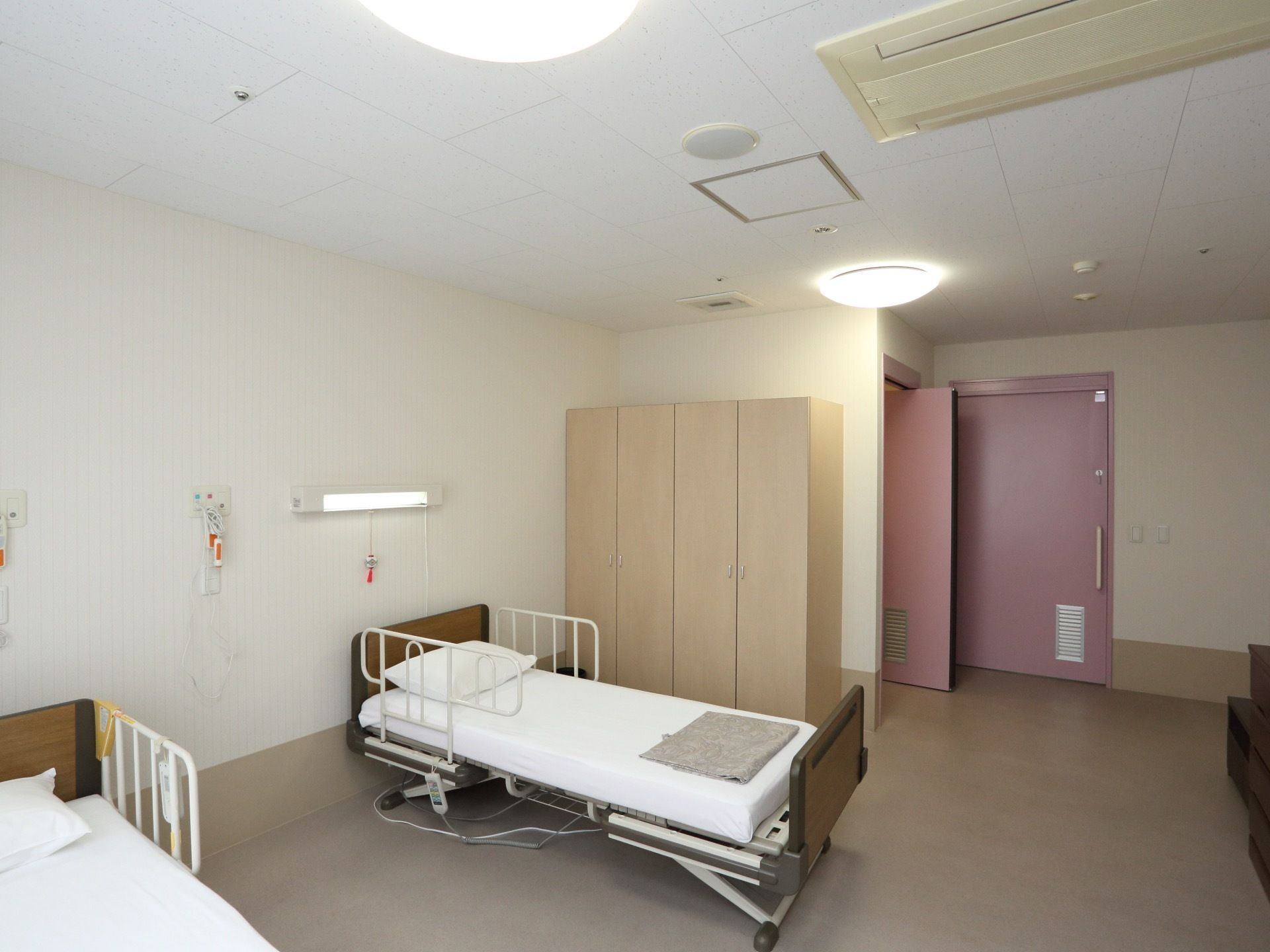 白を基調とした明るい空間である。介護用ベッドが2台と非常呼出しブザー、洋服タンス、エアコン、LEDライトが完備されている。