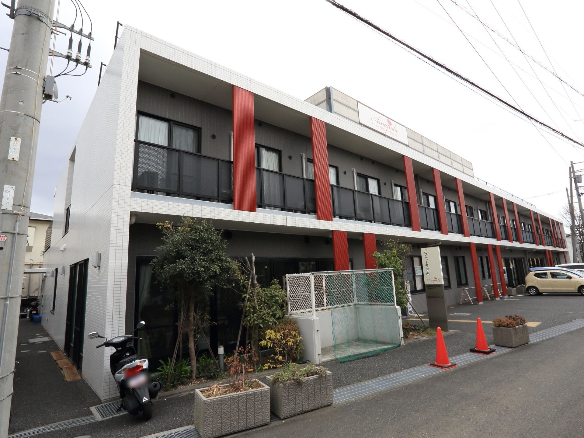 2階建てのモダンな建物である。居室にはバルコニーが完備されている。目の前が駐車場なので移動が楽である。