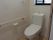 便器近くの壁に手すりが設置されているトイレである。窓があり、小花の壁紙が使われているなど、家庭的な雰囲気がある。