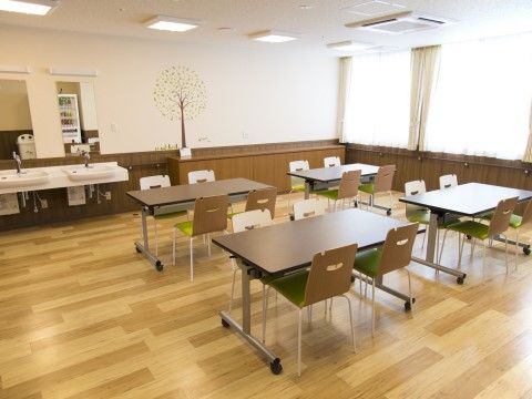 椅子の背もたれは茶色で、シートには黄緑色が入っている。テーブルセットのほかに、洗面台が複数用意してある。