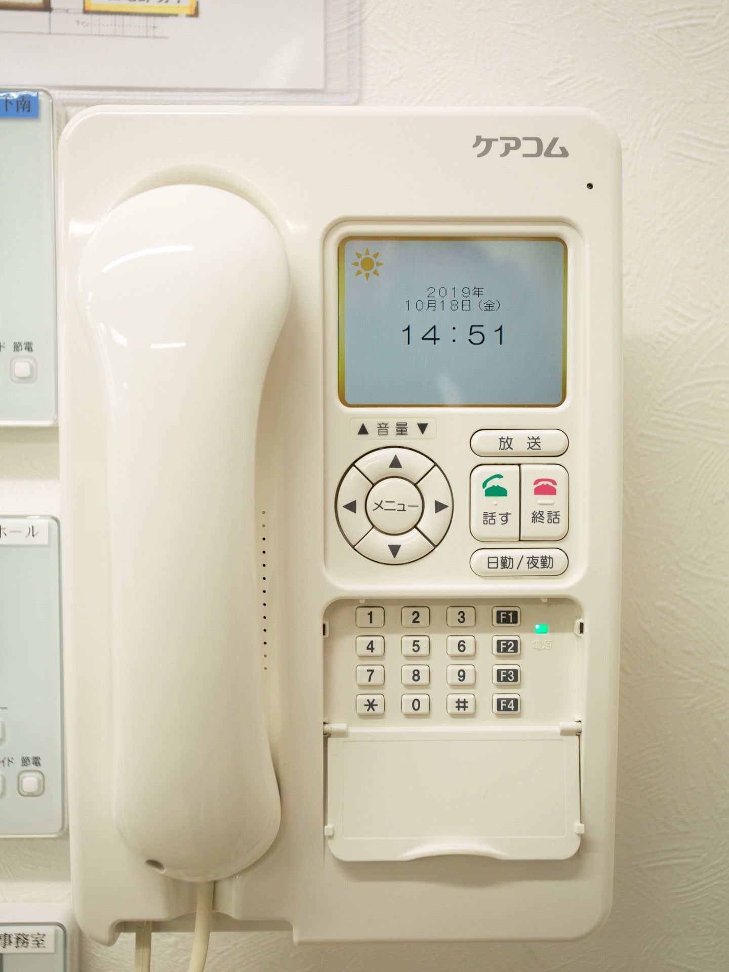カラーモニターが付いている受話器が壁面に取り付けられている。周囲には施設の見取り図と電気系統の操作パネルがある。