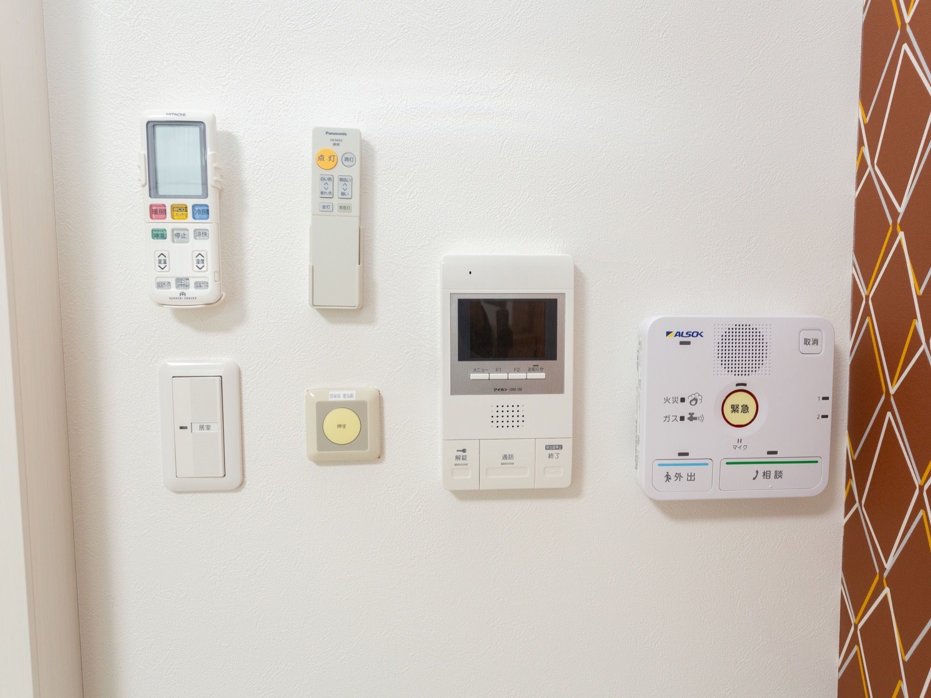照明器具のスイッチの右側にインターホンやセキュリティ関係の操作ボタンが取り付けてある。エアコンのリモコンも収納されている。