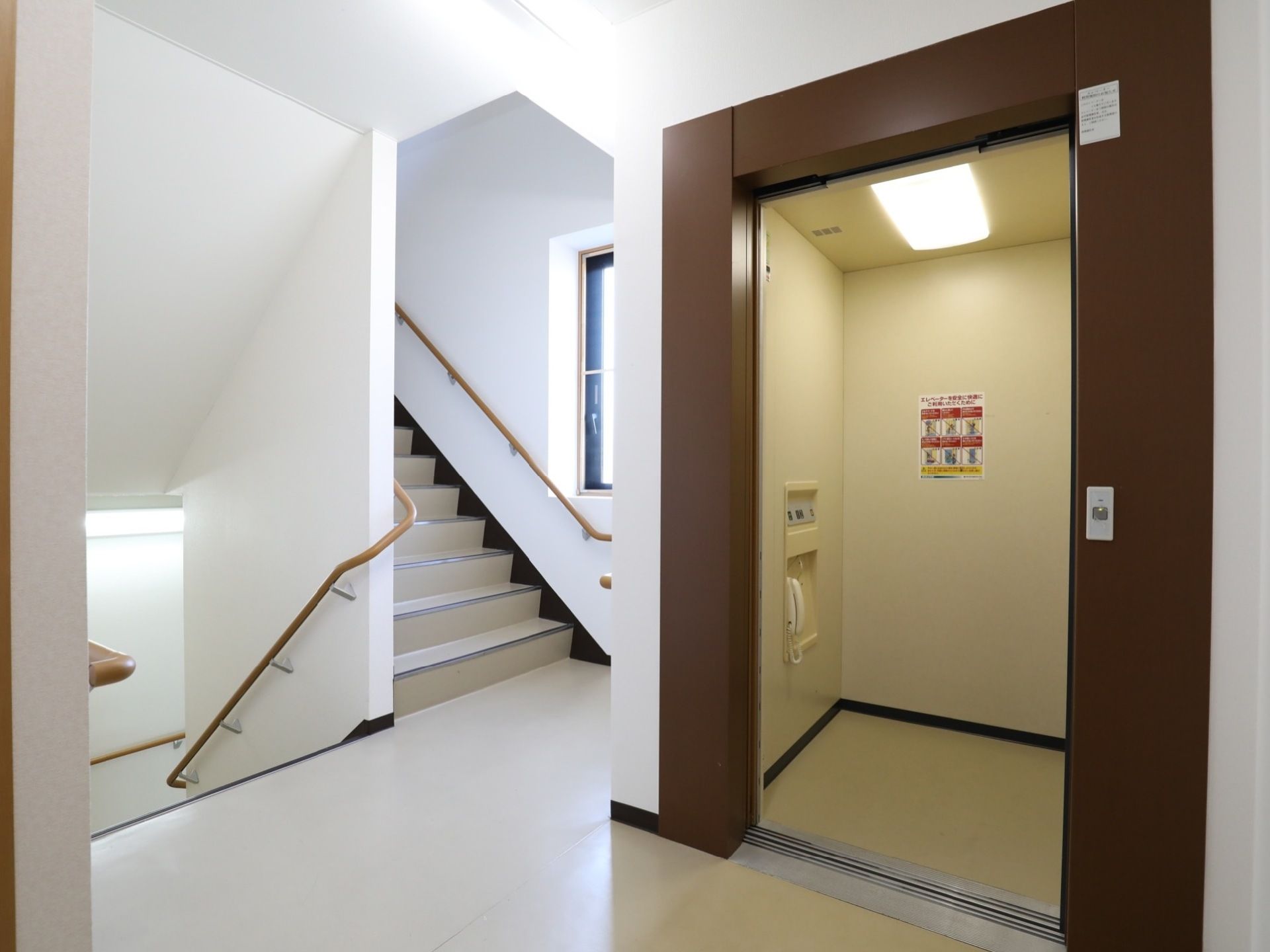 ブラウンを基調とした扉のエレベーターが１基設置されている。中には照明や操作パネル、電話が設置されている。