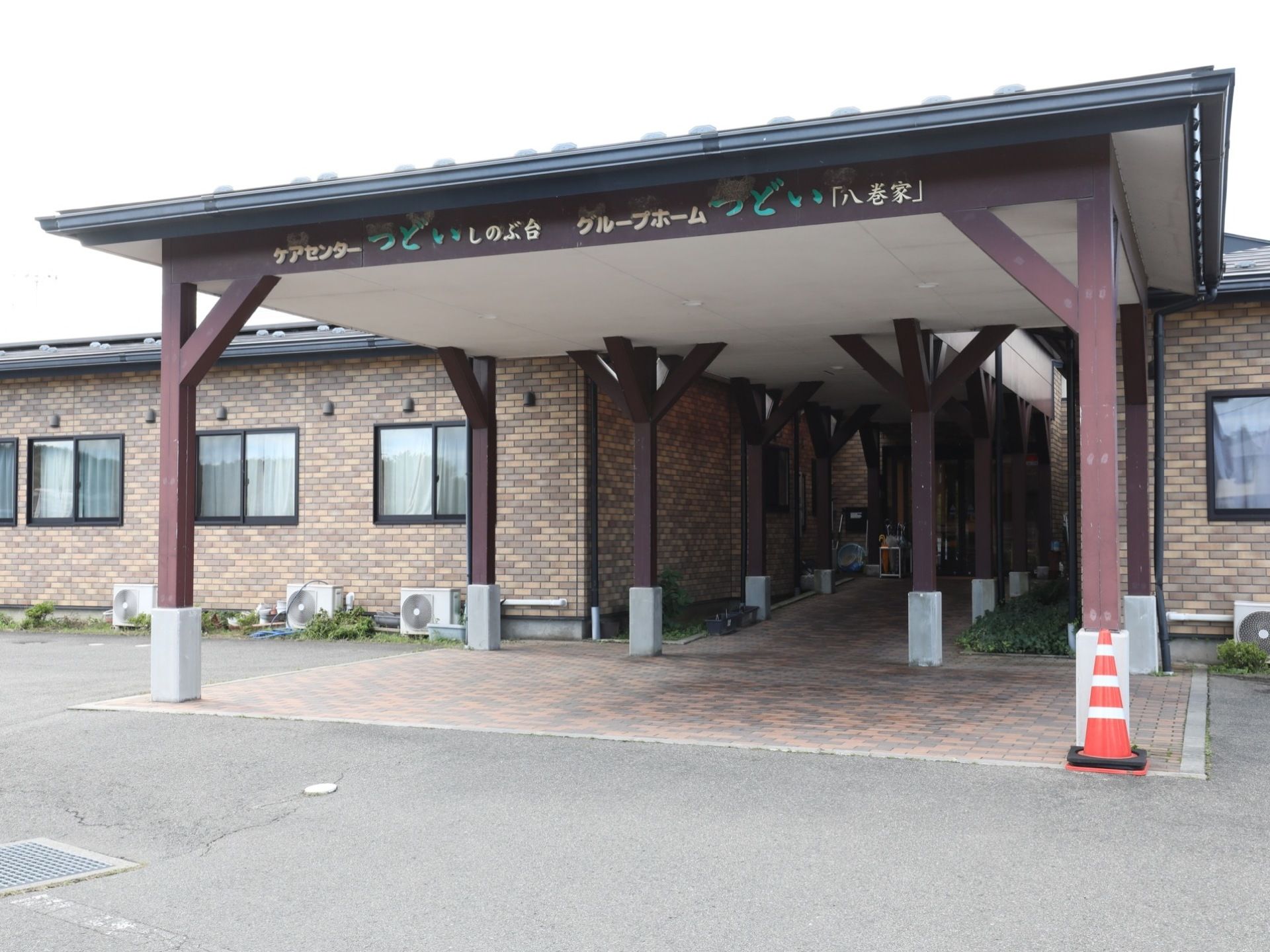 レンガ造りの外壁と大きな屋根のついた入口が特徴の建物である。敷地内には駐車スペースが設けられている。