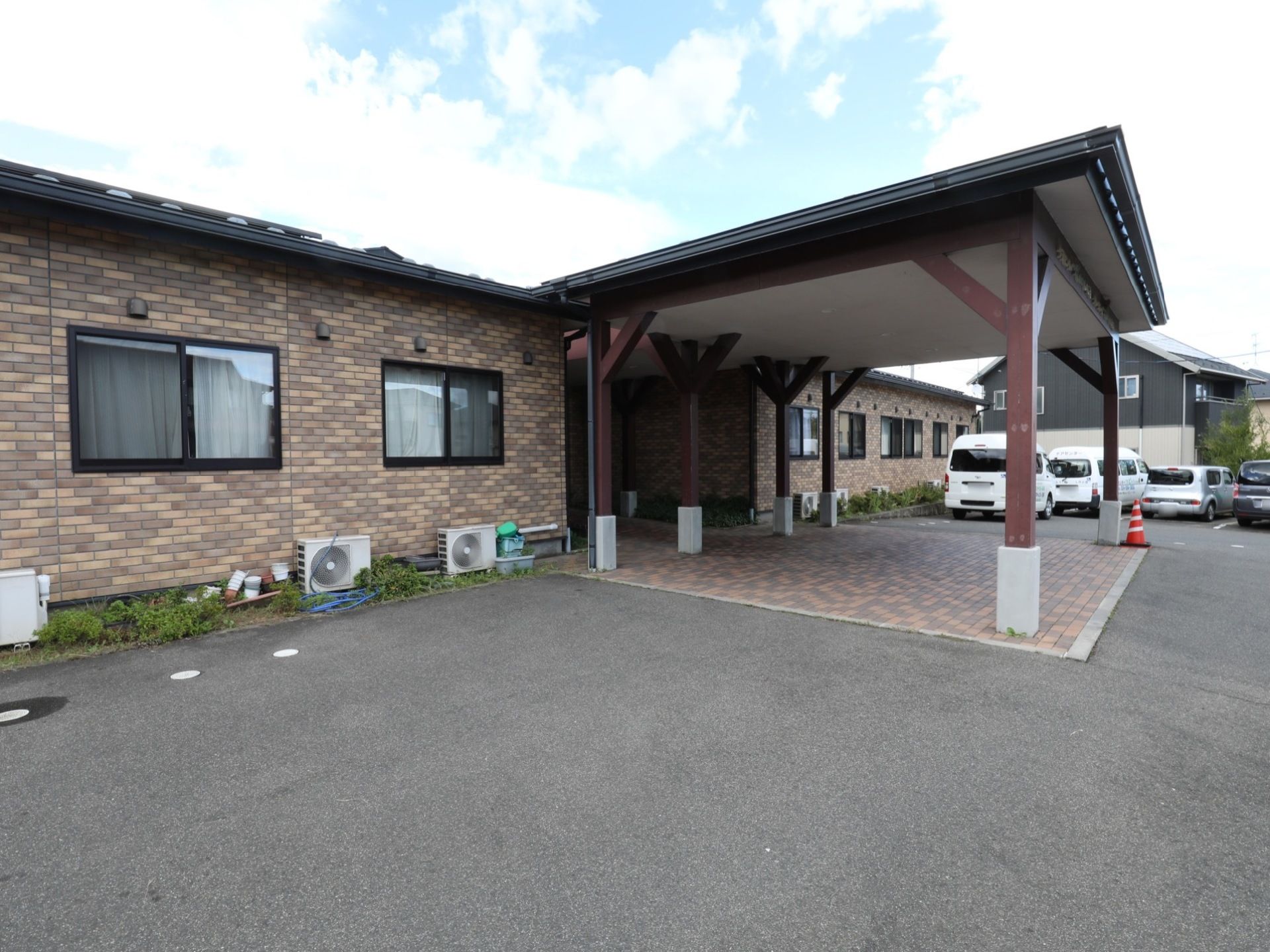 施設は平屋建てであり、玄関には大きな屋根がつけられている。敷地内にある駐車スペースには車数台が停められている。