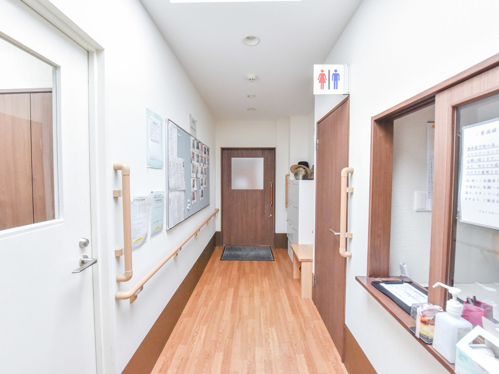 受付前廊下の壁には掲示板が設置されており、写真や様々な通知の紙が掲示されている。廊下突き当りの右側にはロッカーがある。