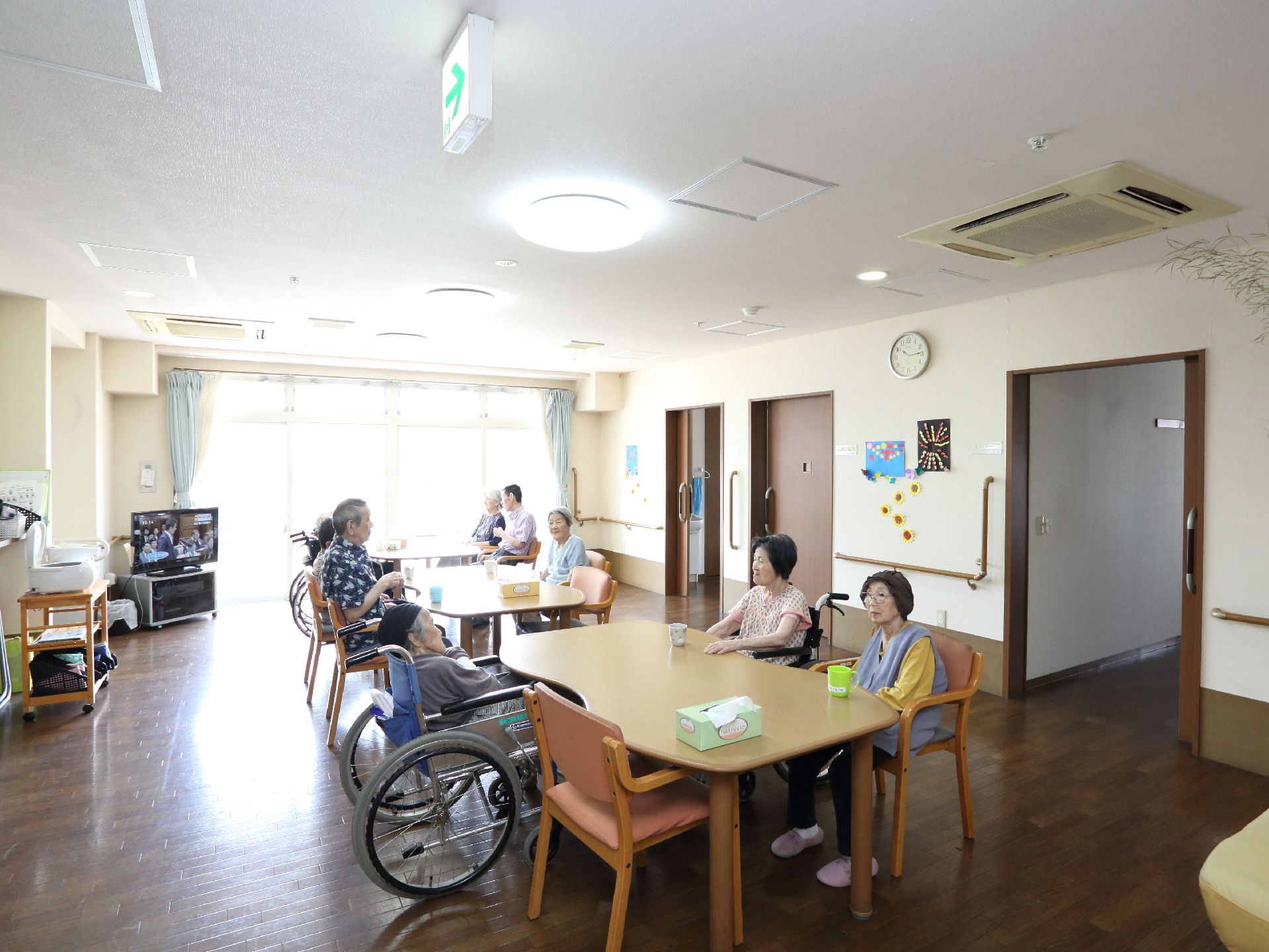 リビングでは多くの入居者が机を囲んで顔を合わせ、団らんすることができる。部屋の隅にはテレビも設置されている。