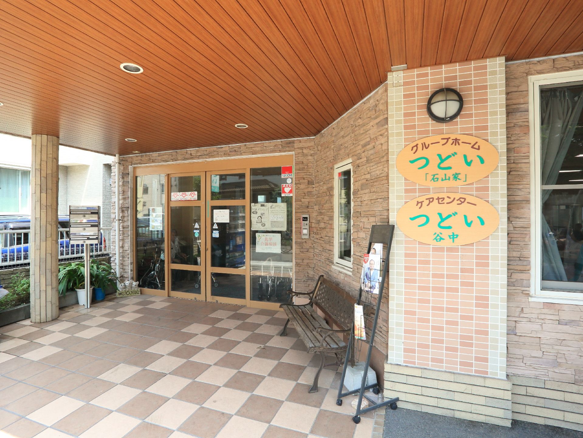 入り口には施設名の書かれた表札が掲げられており、目印となっている。入り口脇にはいくつかの植物が植えられている。