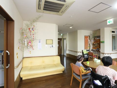 黄色いソファーの横に、七夕の笹の葉が飾られた共有スペース
