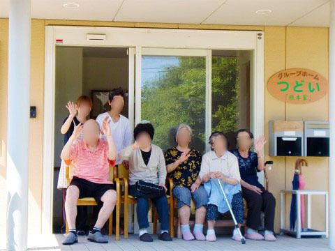 ベンチのある玄関で、微笑みあうスタッフとご入居者様