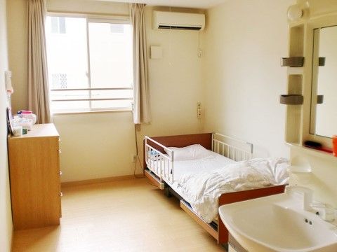 リクライニングベッドとチェスト、洗面台が完備してある。エアコンがついているので、年中快適な室温で生活できる。