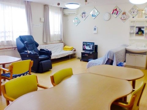 マッサージチェアが部屋の中央に置かれている。テレビやソファー、ダイニングテーブルが置かれていて、のんびり過ごすことができる。
