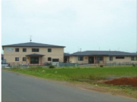 2階建ての建物と横長い平屋からなる、当施設の黄色い外観