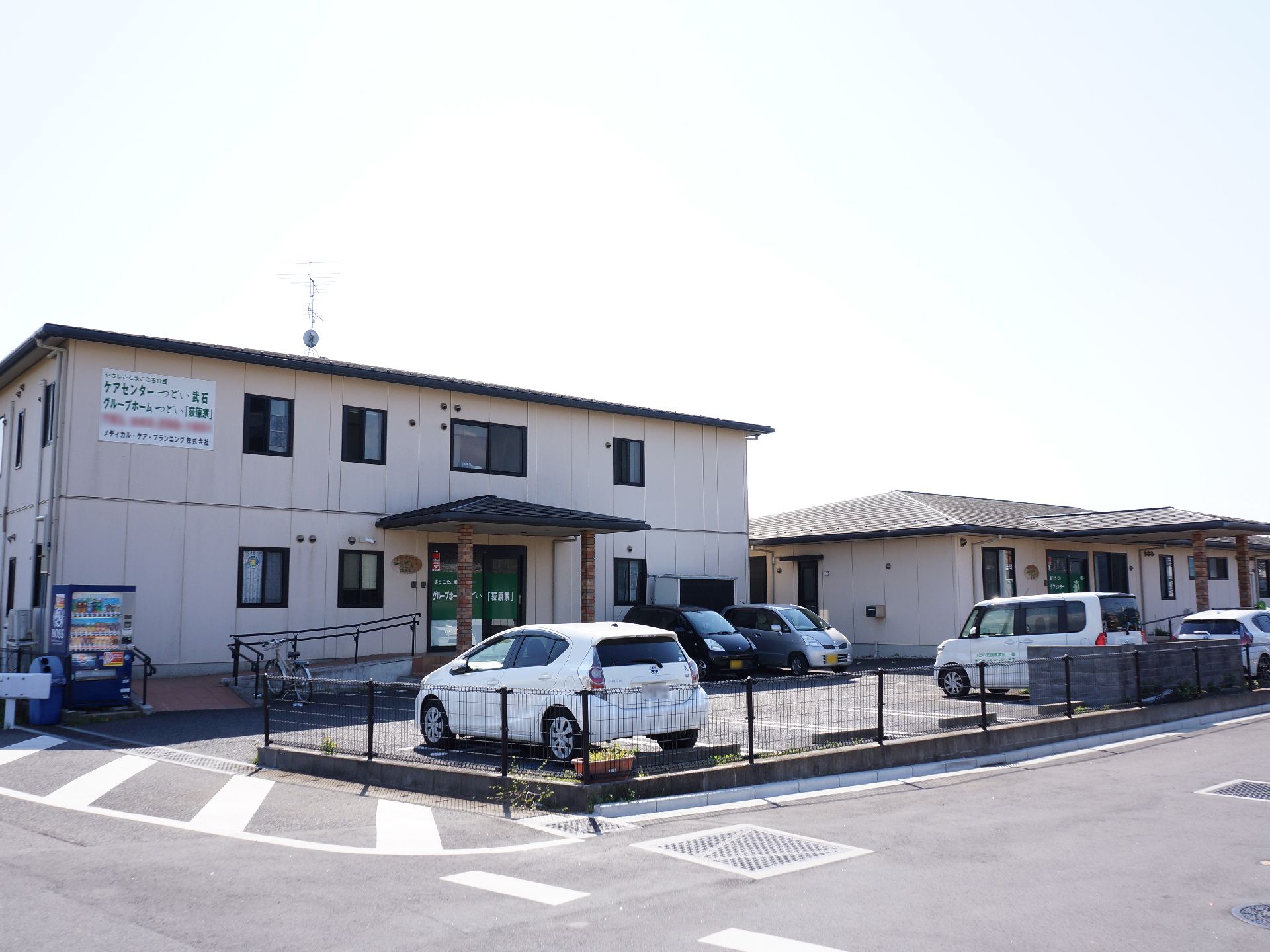 施設の周囲は視界を遮る建物がなく日当たりが良い。玄関前に広い駐車スペースが設けられている。同事業者が経営するデイサービスが併設されている。