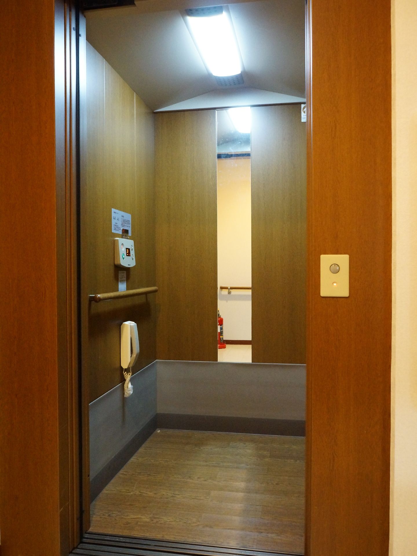 エレベーター内部には手すりと緊急通報用の電話が設置されている。車椅子で操作しやすい位置にボタンがあり、鏡があるので乗降時に後方確認しやすい。