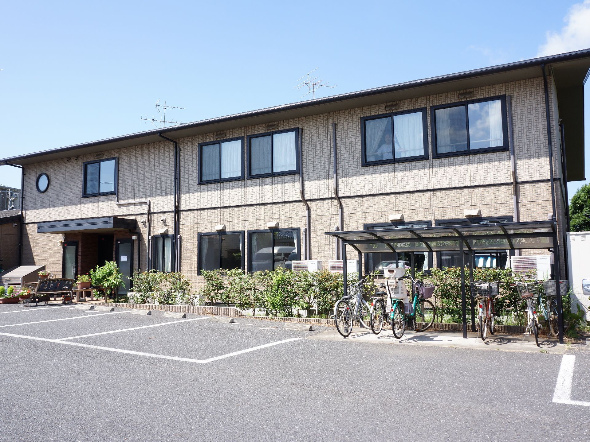 グループホームは2階建ての建物になっている。広々とした敷地には駐車場があり、屋根のついた駐輪場も用意している。