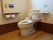 トイレには洗浄機能がついた洋式便器を設置している。また壁には緊急時の呼び出しボタンがあり、手すりが取り付けられている。