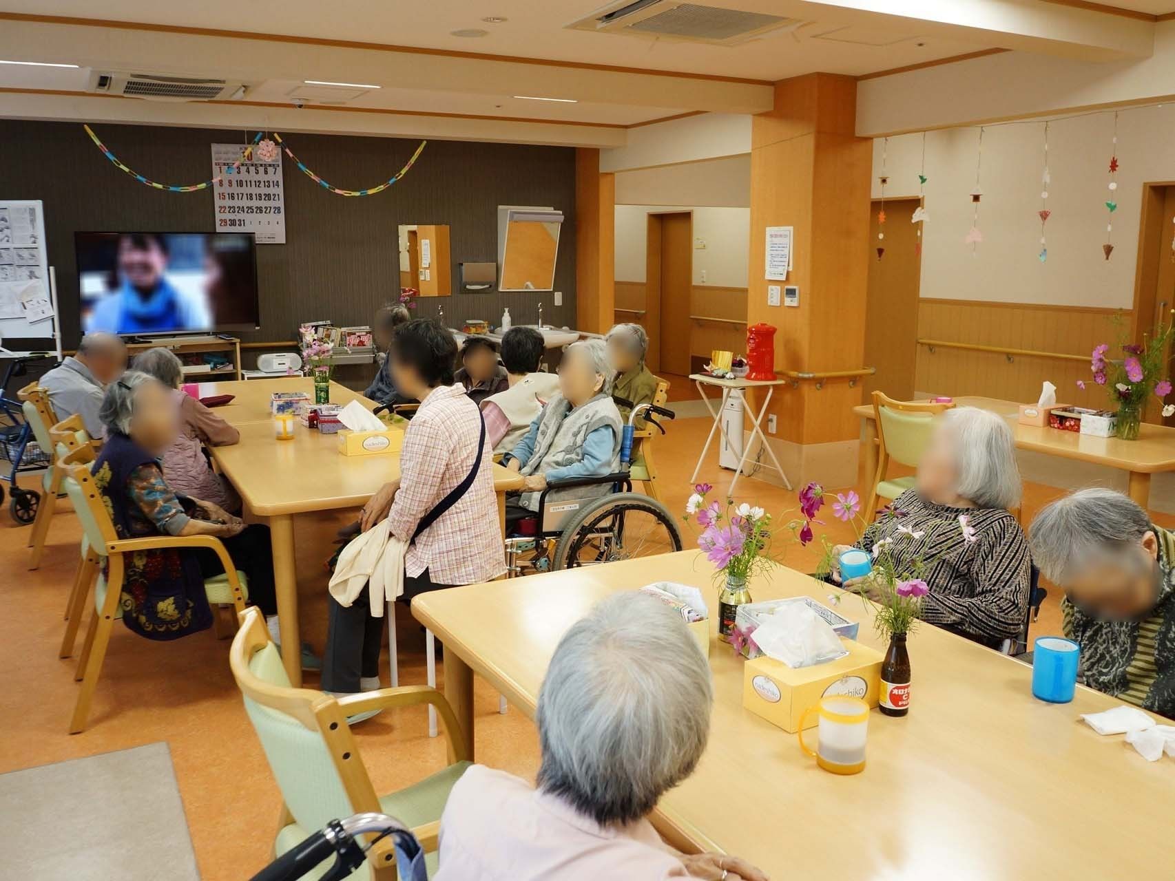 共有スペースには、テレビを見ている人、スタッフと談笑している人など、様々な形で楽しくくつろいでいる入居者様がいる。