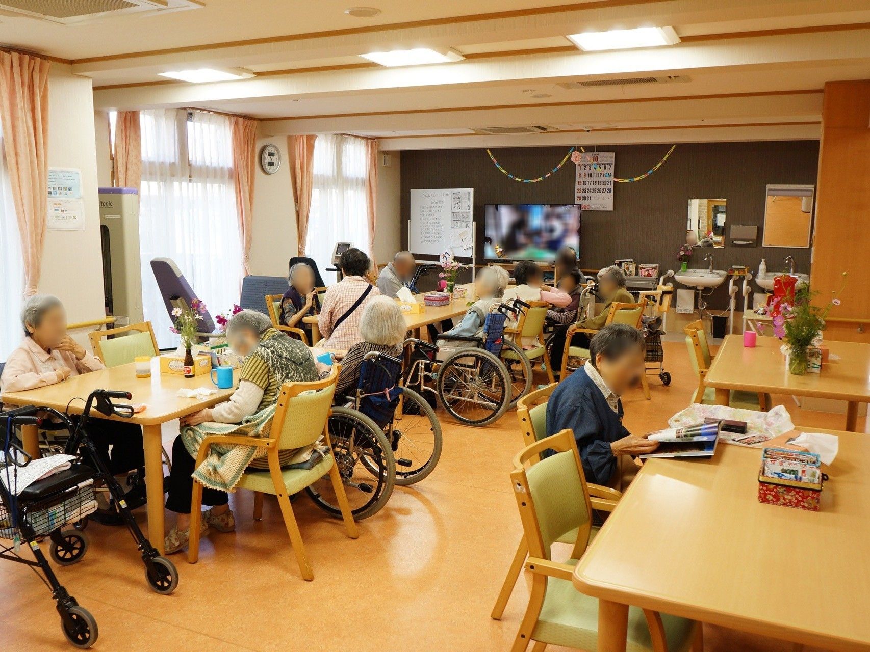 共有スペースにはたくさんの入居者様がおり、雑誌を読んでいたり、テレビを見ていたり、談笑をしている人など思い思いにくつろいでいる。