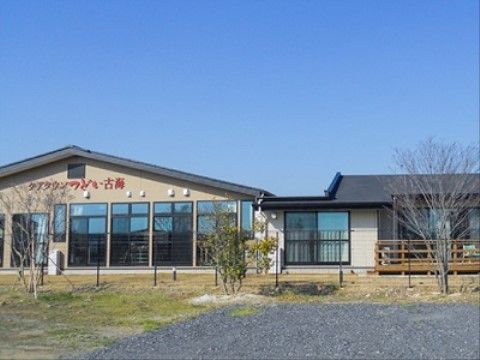 緩やかな傾斜の大きな屋根が載った、平屋の新しい建物。大きな掃き出し窓が並んでいる。一部には木製のテラスが付いている。