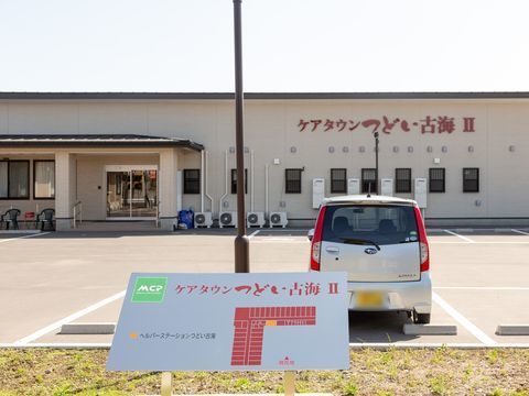 公道に面した植え込みには、外向きに施設看板が取り付けられている。金属の板が斜めに傾斜が付いた形になっている。