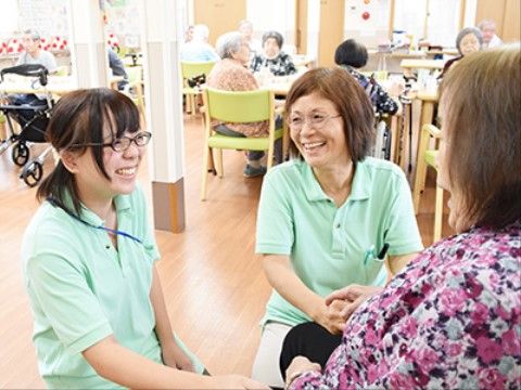 ご入居者様の膝に手を置いて、近い距離でお話しするスタッフ