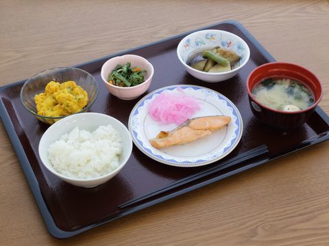 トレイの上に乗った食事の一例。ごはん、味噌汁のほか、メインの焼き魚、サラダ、小鉢2種は、煮びたし、あえ物などが盛り付けられている。