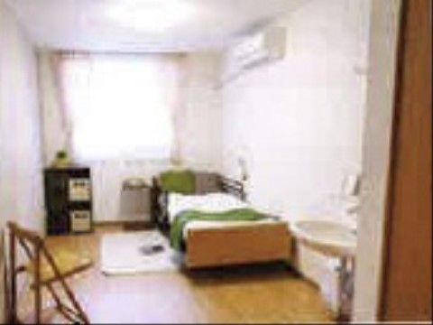 右手に介護用ベッドが設置されている。左手奥には窓とカーテンが設置されていて、室内を明るく照らしている。