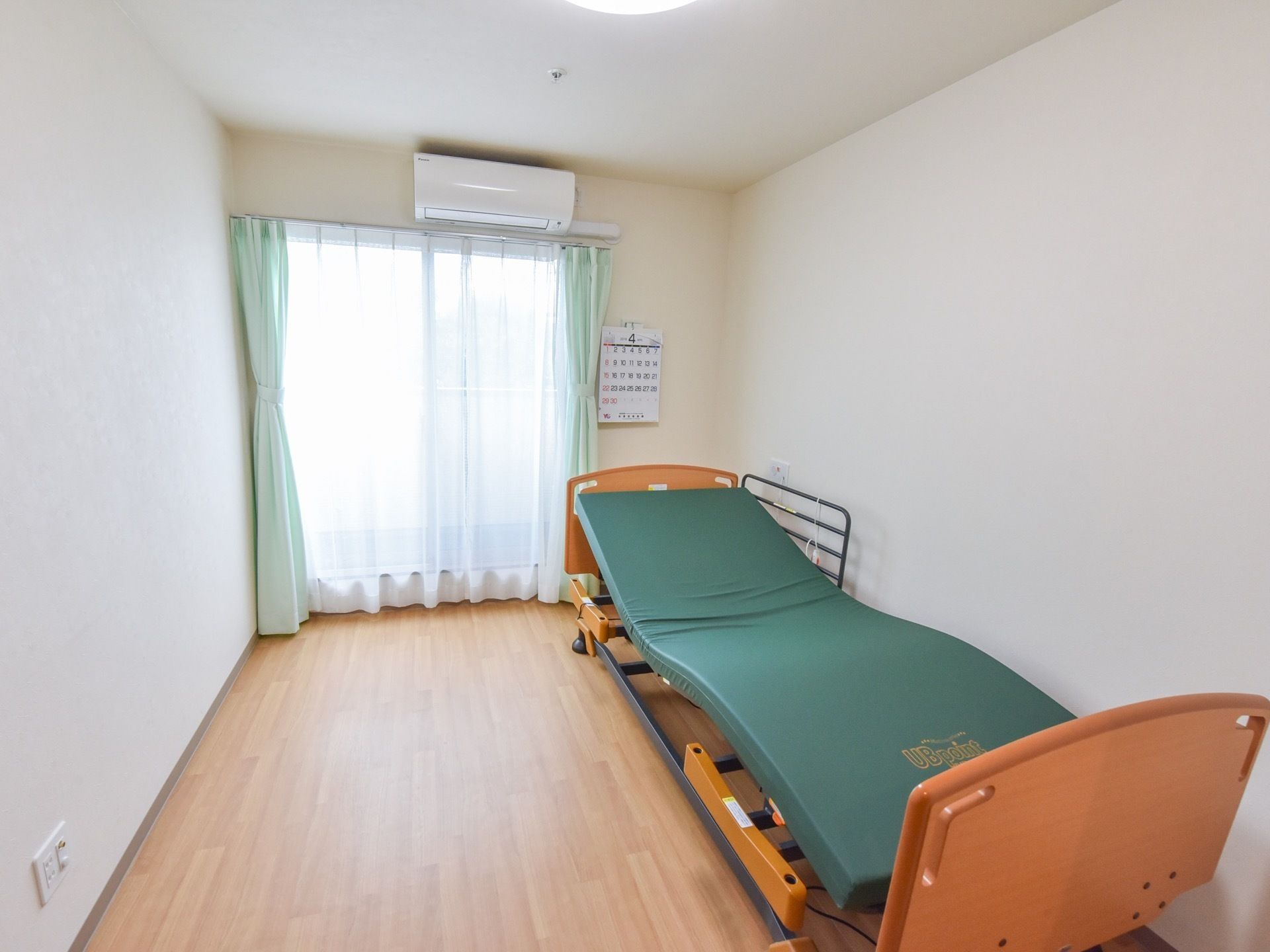 広々としたフローリング仕様の居室には、大きな介護用ベッドが置かれている。簡単なボタン操作でリクライニングが行えるので、楽に寝起きできる。