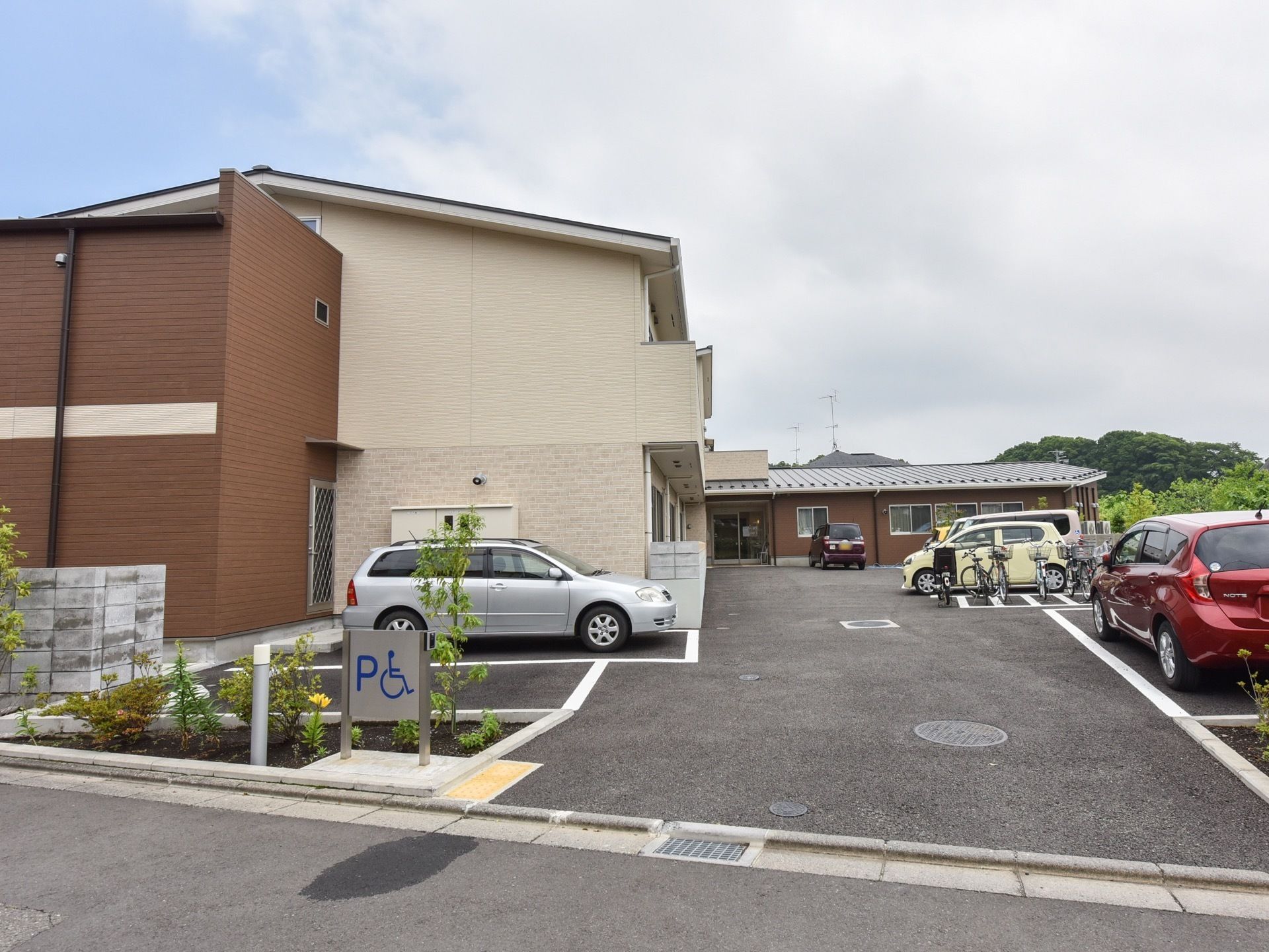施設の入り口に植栽が施された、２階建てのアットホームな雰囲気の施設の外観。敷地内は地面がフラットで、バリアフリーに十分配慮されている。