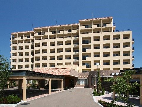 広い敷地を持つ、8階建ての黄色を基調とした外壁の外観